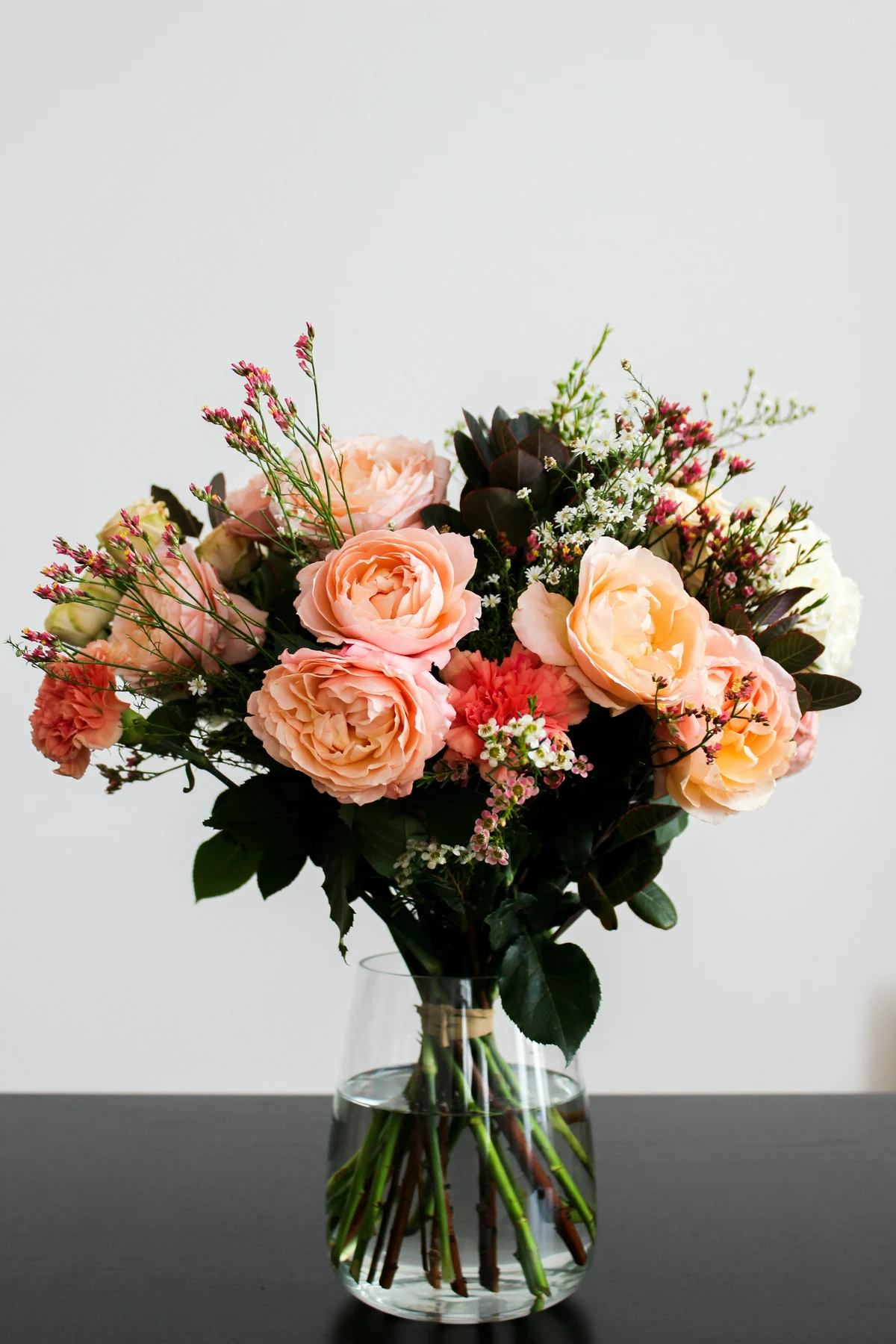 Peach and cream roses with small white flowers and dark green leaves.